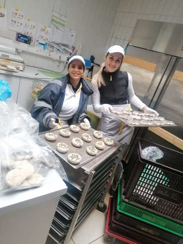 Zwei Frauen in Billa-Uniformen in einer Backstube beim Halten von Blechern mit Gebäck